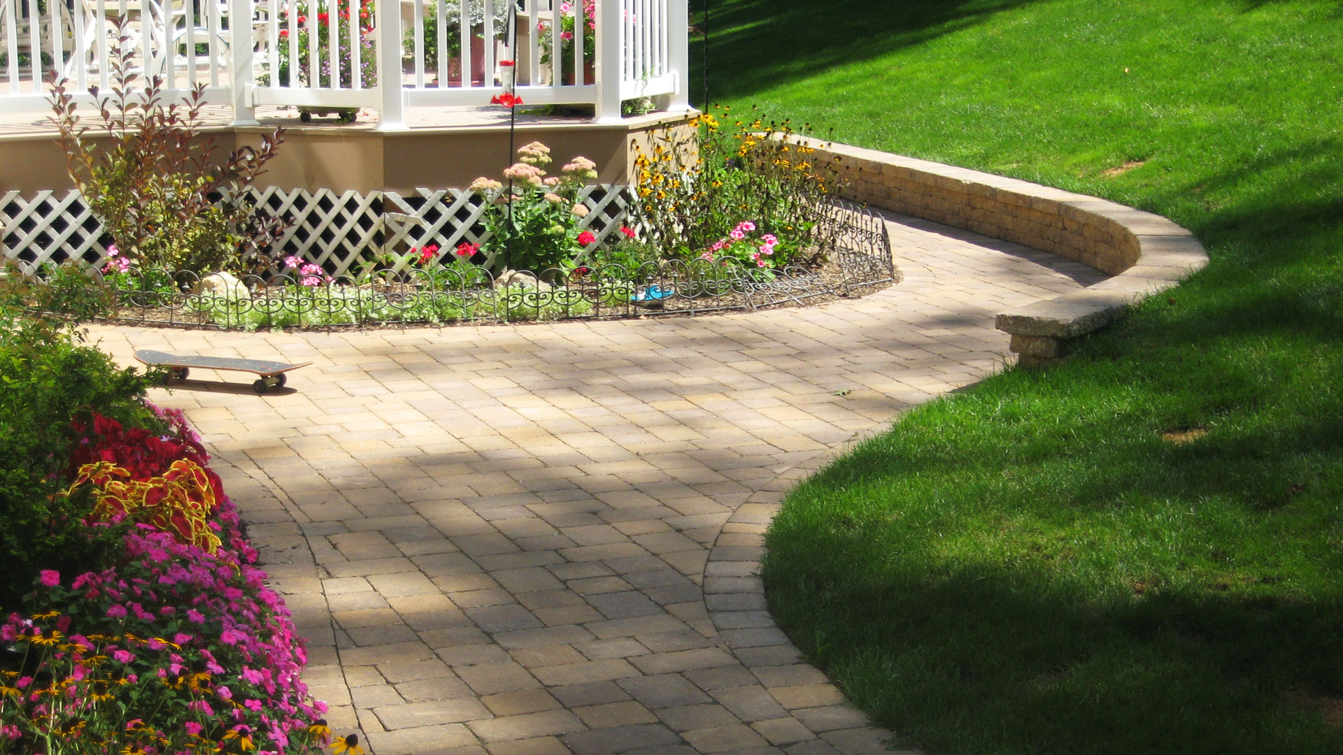 Curved paver patio with seating wall and perennial flowers