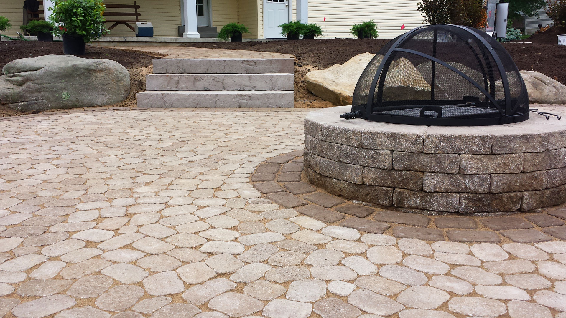 Close up of fire pit surrounded by cobblestone style pavers