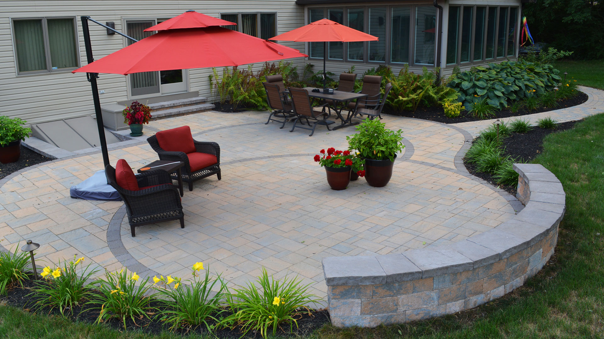 Large brick paver patio with furnishings and seating wall